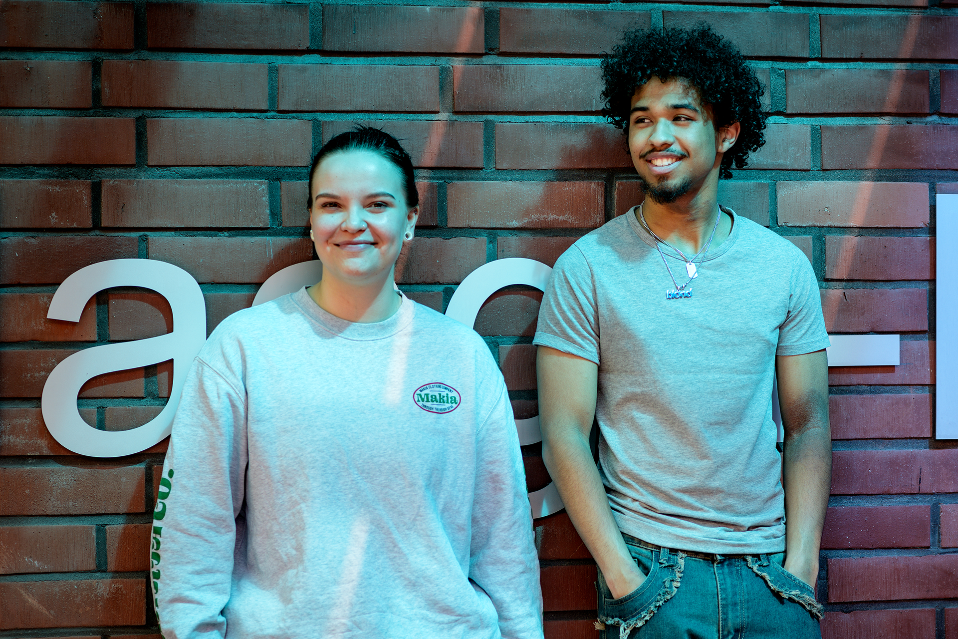 kaksi opiskelijaa tiiliseinän edessä